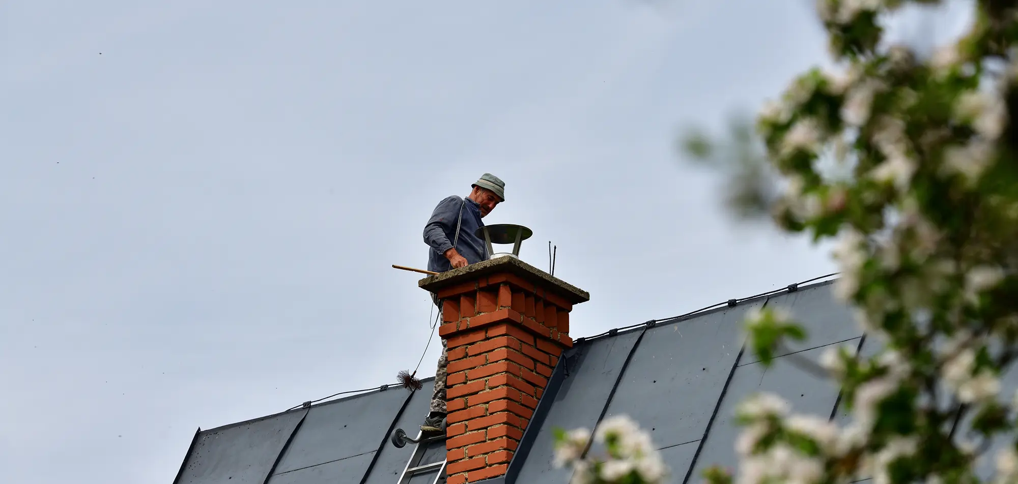 Technician inspecting a residential chimney flue and roofline